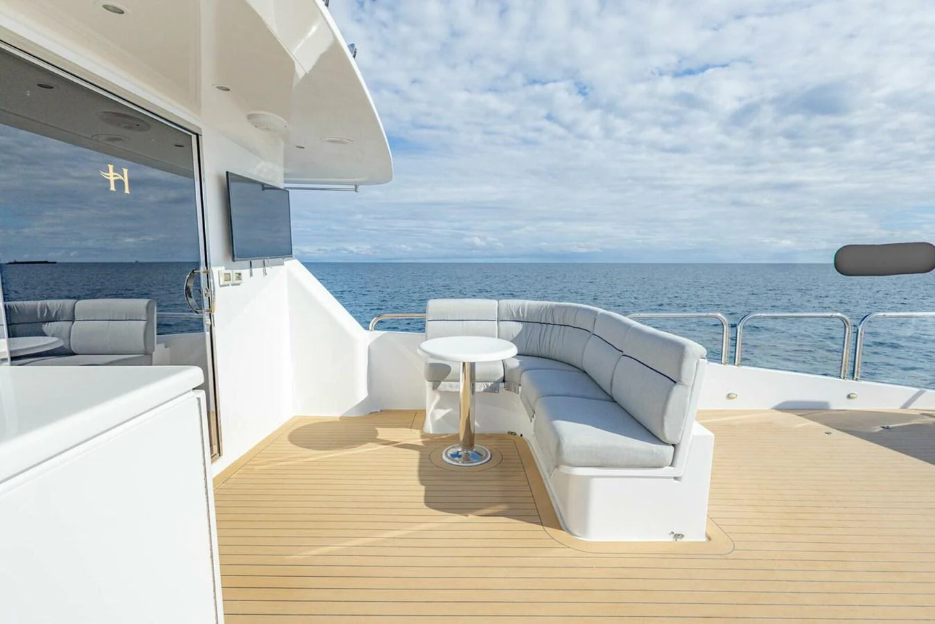 The aft deck features a comfortable seating area with a round table, perfect for enjoying the ocean views. aboard BOBBI TOO Yacht for Sale
