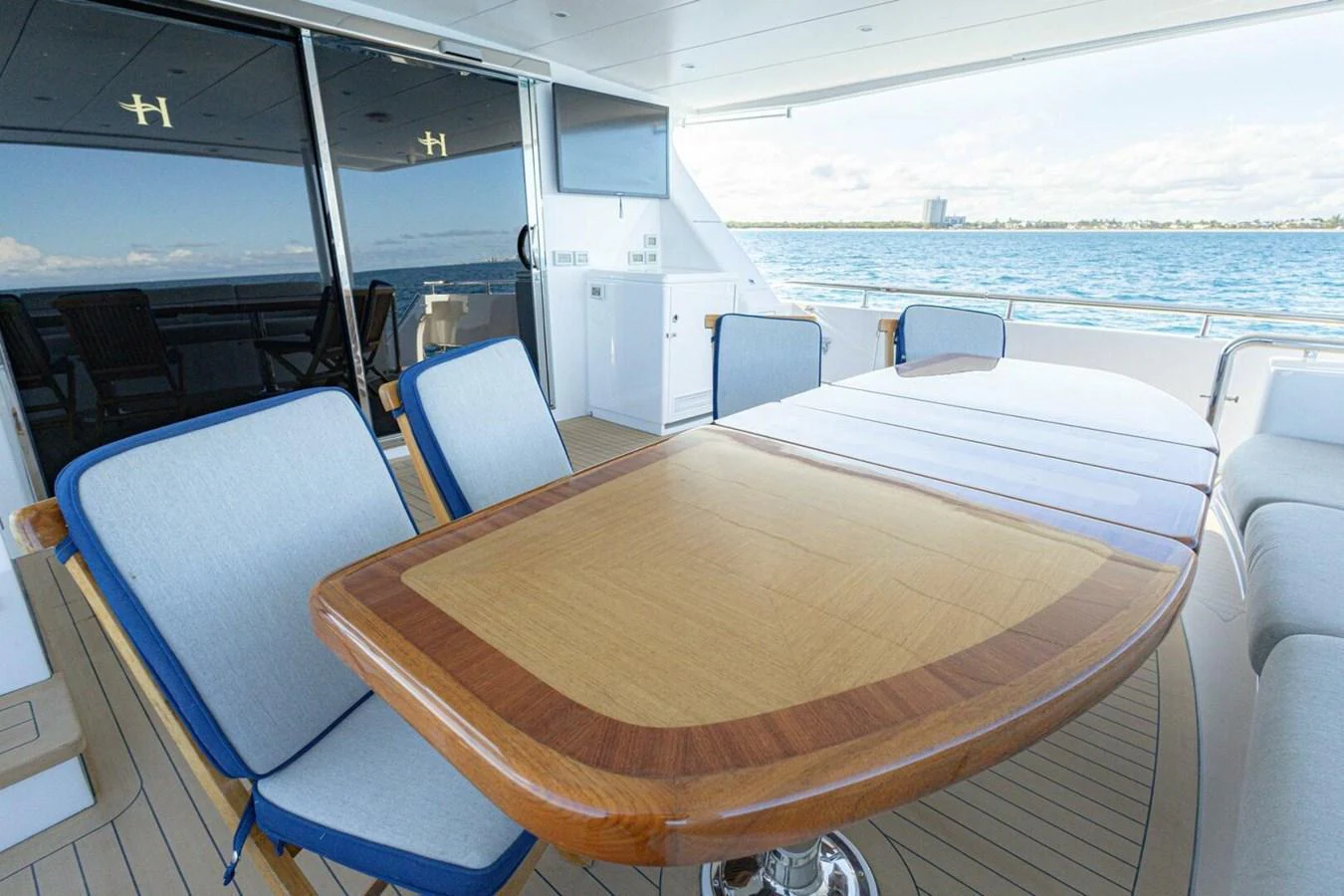 The aft deck features a spacious dining area with a polished wooden table and comfortable seating, perfect for al fresco meals with a view. aboard BOBBI TOO Yacht for Sale