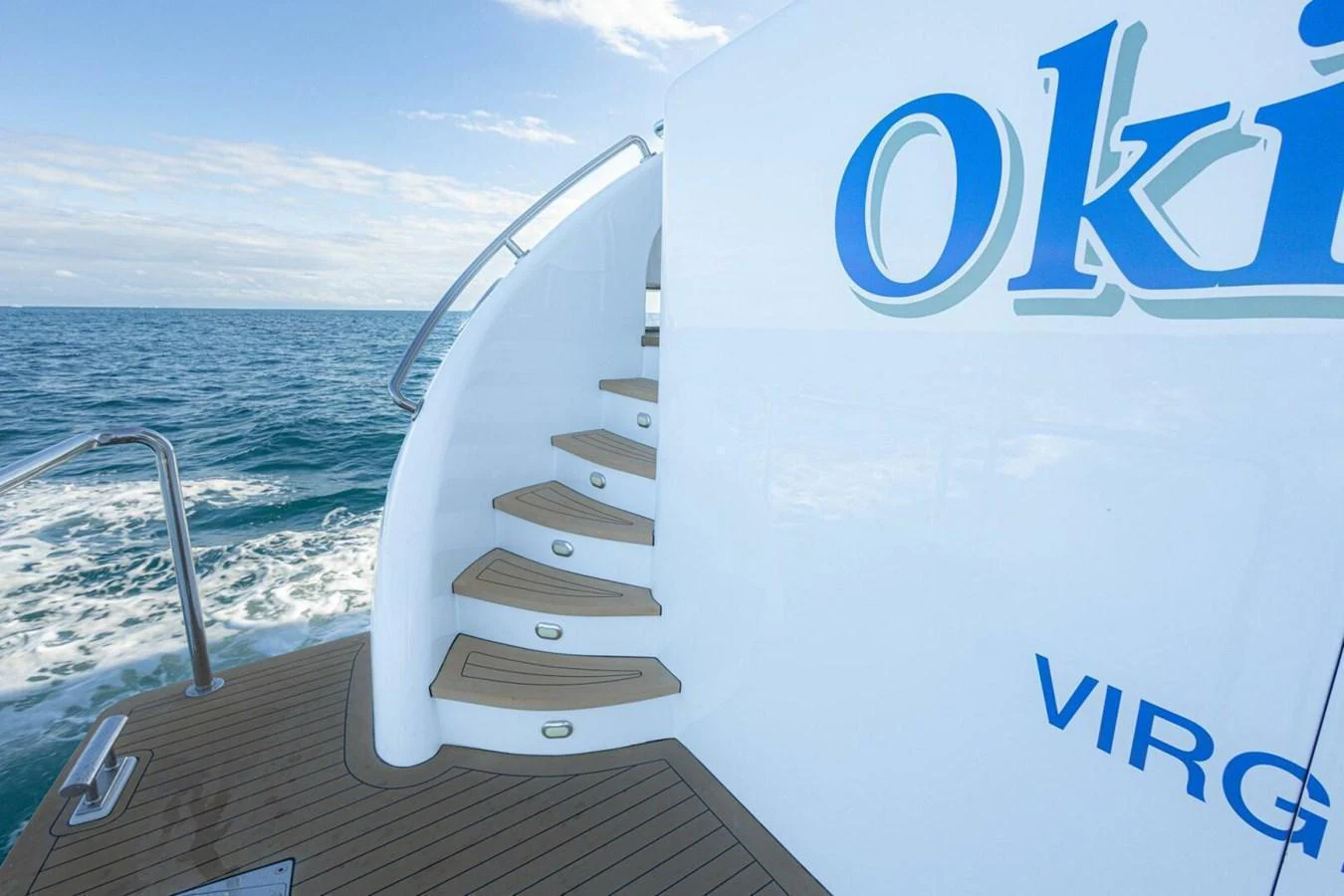 A sleek staircase on the yacht leads up from the deck, with the ocean in the background. aboard BOBBI TOO Yacht for Sale