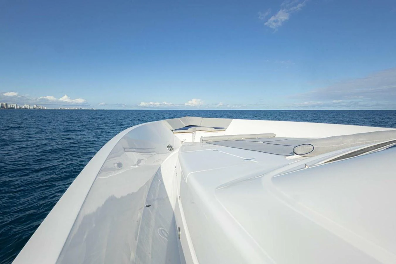 The sleek bow of the yacht cuts through the calm blue waters under a clear sky. aboard BOBBI TOO Yacht for Sale