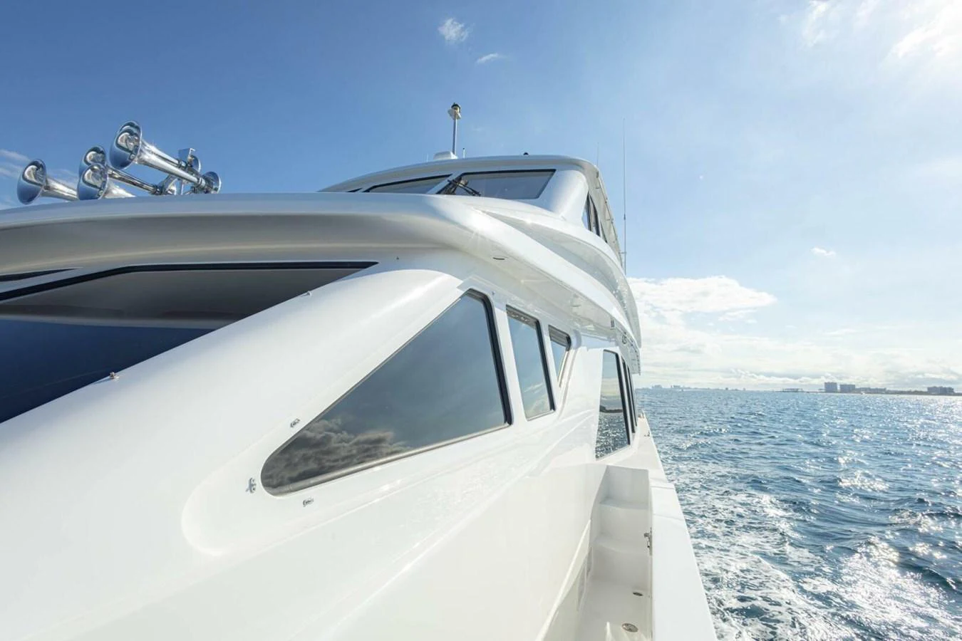 A sleek yacht glides through the water under a clear blue sky. aboard BOBBI TOO Yacht for Sale