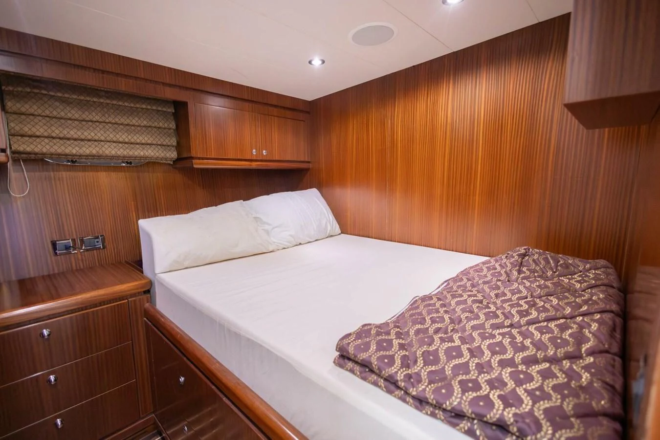 The stateroom features a cozy bed with elegant wood paneling and ambient lighting. aboard BOBBI TOO Yacht for Sale