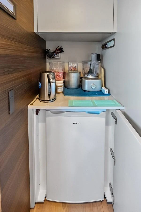 a small kitchen with a small refrigerator aboard LUMPASAURUS Yacht for Sale