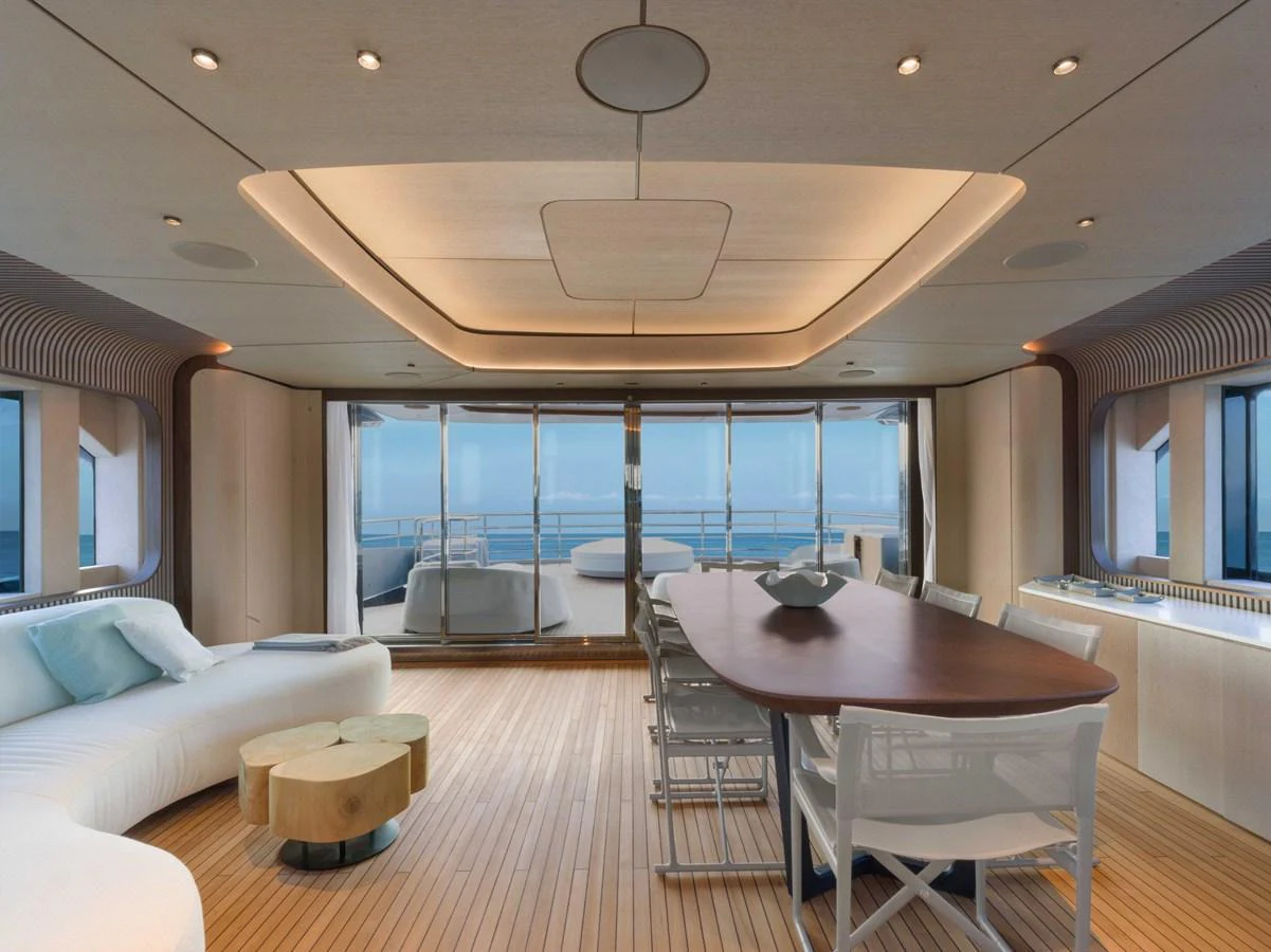 The yacht's dining area features a sleek table with ample seating and panoramic ocean views. aboard PESA II Yacht for Sale