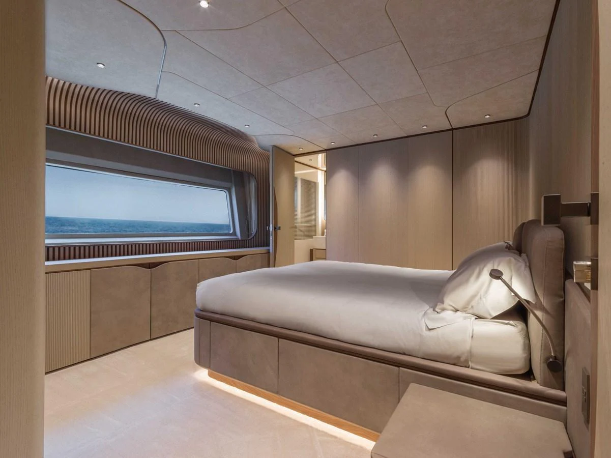 The stateroom features a large bed, modern furnishings, and a panoramic window with an ocean view. aboard PESA II Yacht for Sale