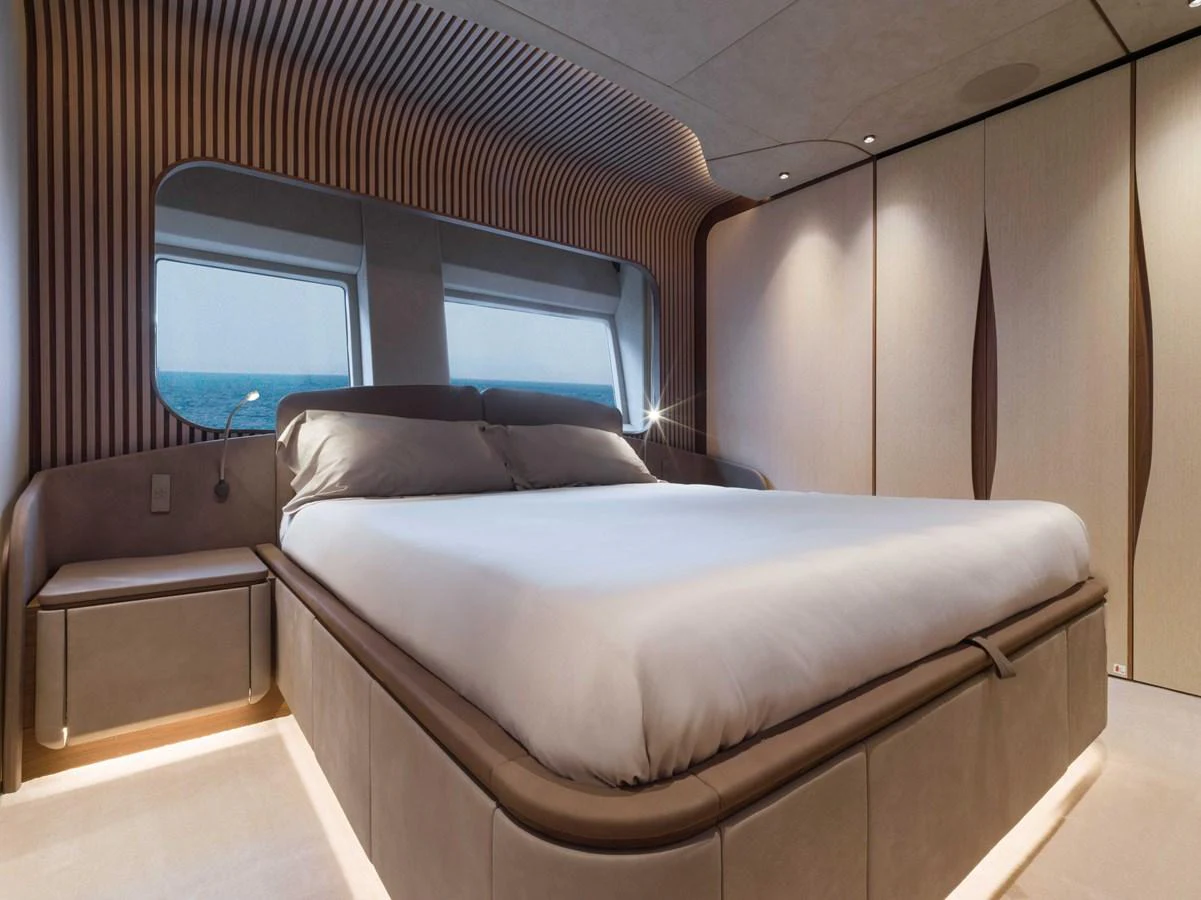 The master stateroom features a luxurious bed with modern design elements and large windows offering stunning ocean views. aboard PESA II Yacht for Sale