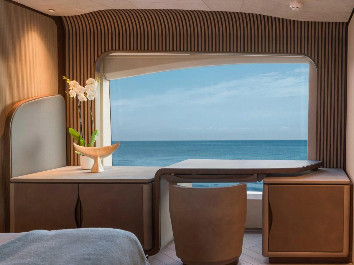 A serene stateroom with a desk and a large window offering a stunning ocean view. aboard PESA II Yacht for Sale
