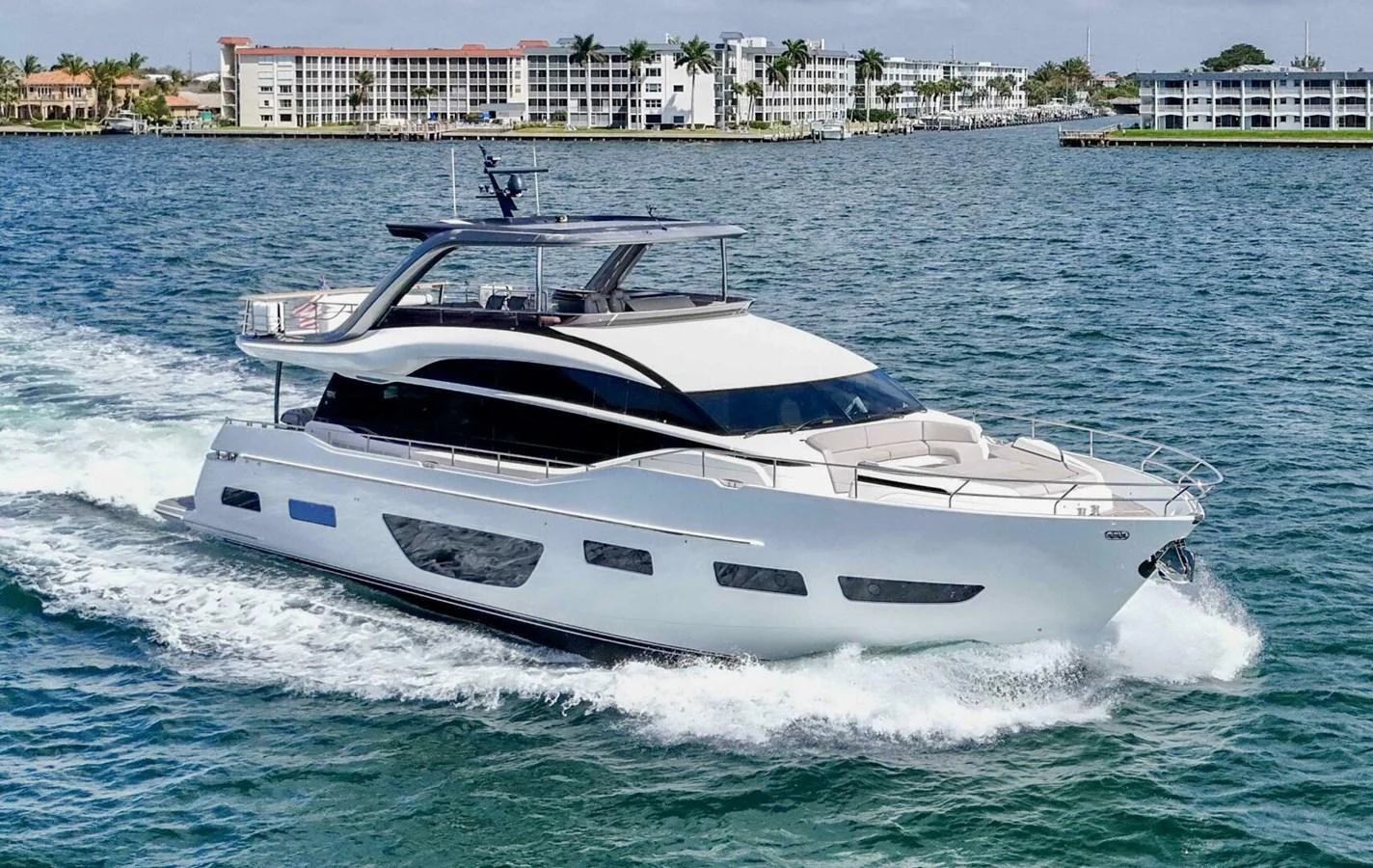 A sleek and modern yacht cruising on the water with a scenic coastal backdrop. aboard RECORD YEAR Yacht for Sale