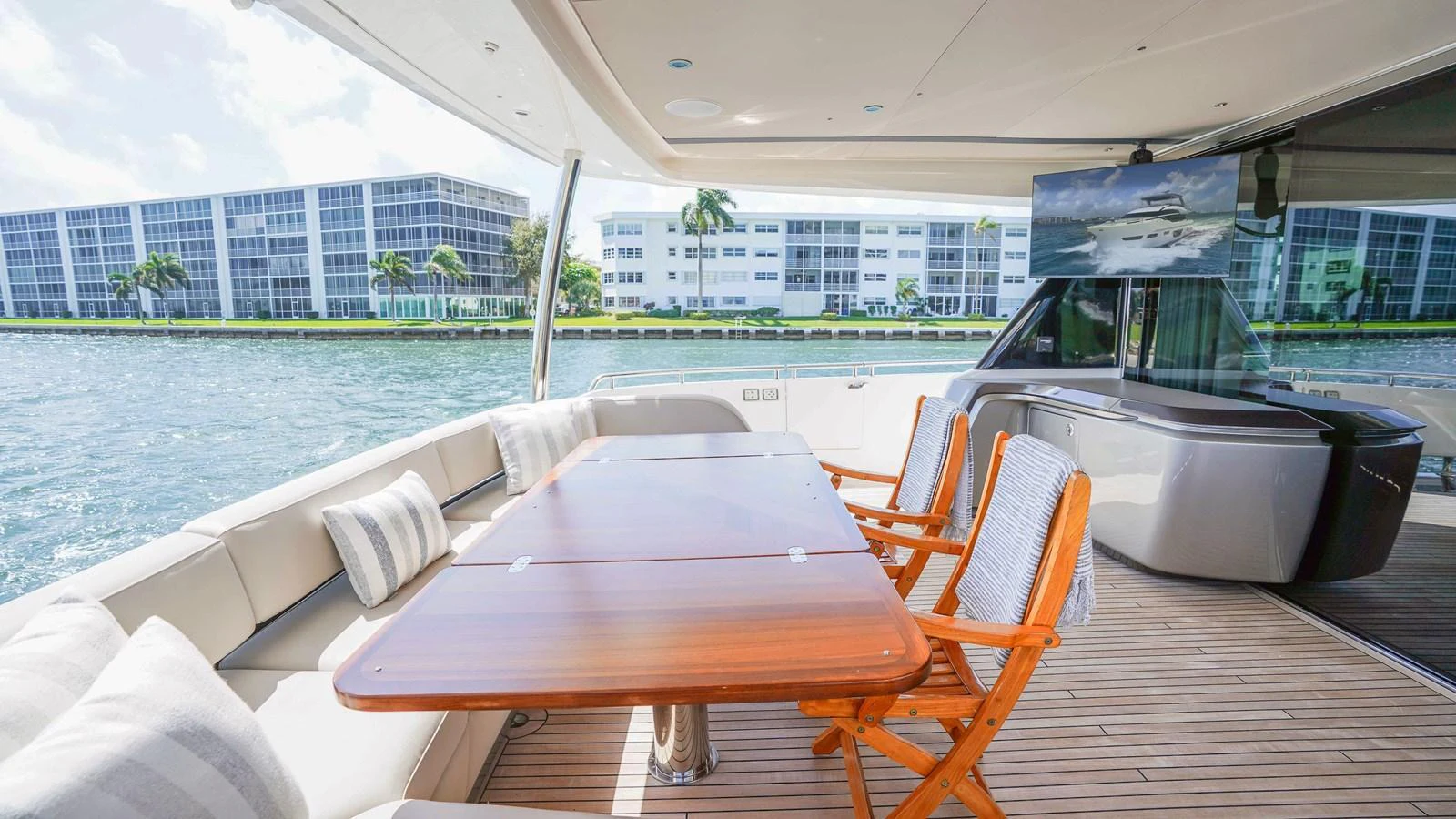 The aft deck features a spacious dining area with a polished wooden table and comfortable seating, perfect for alfresco meals with a view. aboard RECORD YEAR Yacht for Sale
