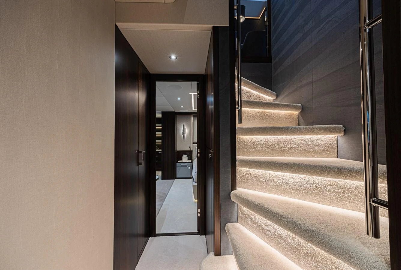A luxurious staircase with soft lighting leads to the lower deck, showcasing elegant interior design. aboard HIDEOUT Yacht for Sale