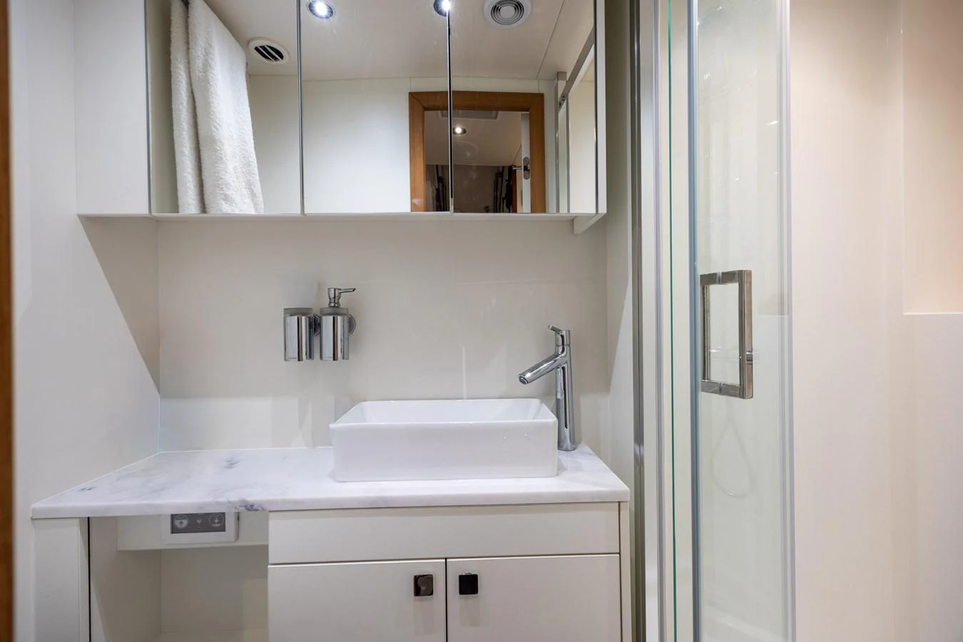A sleek and modern yacht bathroom featuring a vessel sink and a glass-enclosed shower. aboard HIDEOUT Yacht for Sale