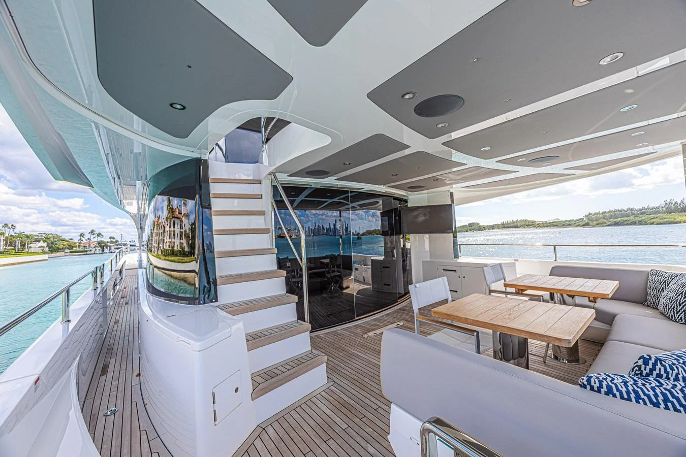 The aft deck features a spacious seating area with a dining table and a staircase leading to the upper deck. aboard HIDEOUT Yacht for Sale