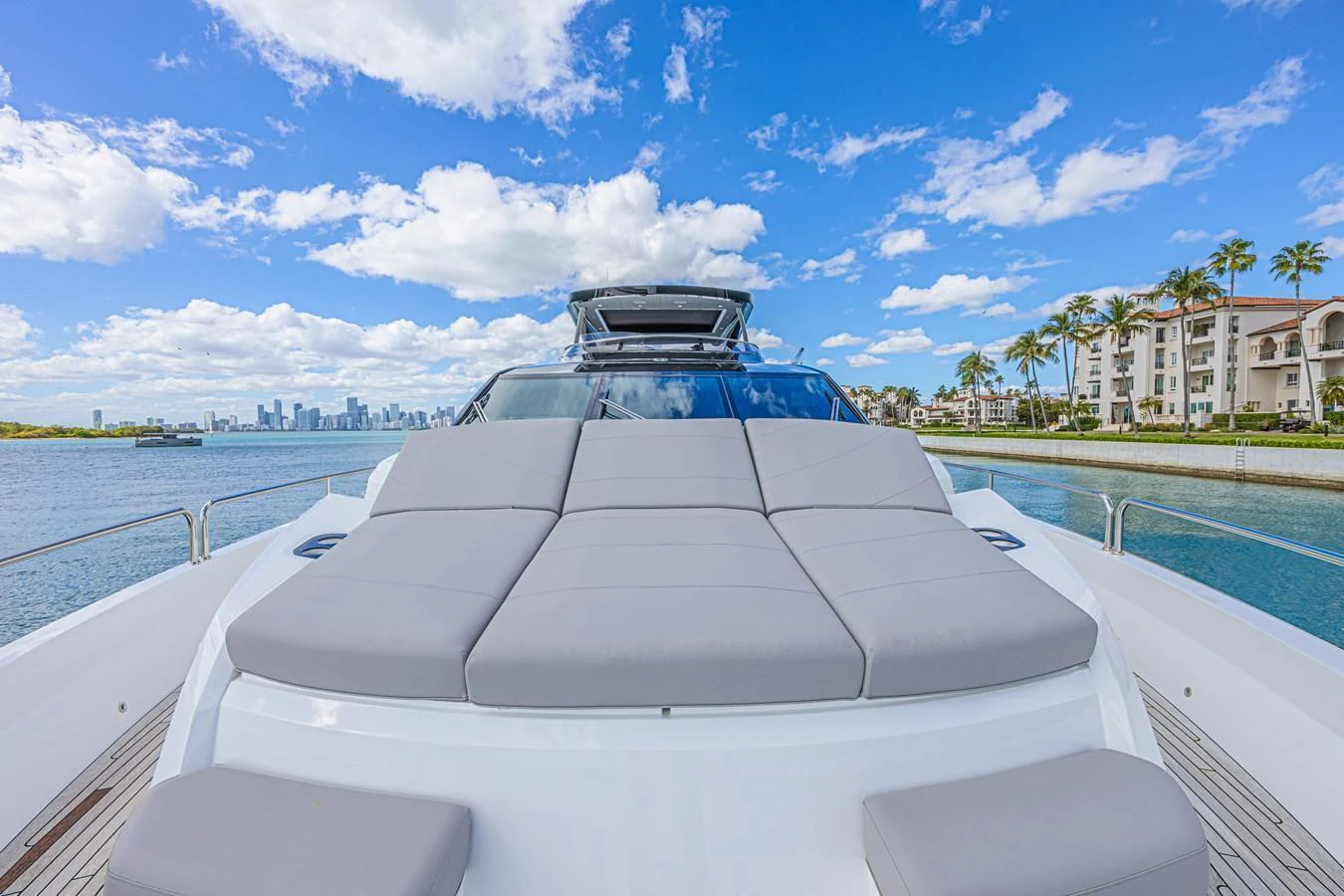 The yacht's foredeck features a spacious sunbathing area with plush cushions, set against a stunning waterfront backdrop. aboard HIDEOUT Yacht for Sale
