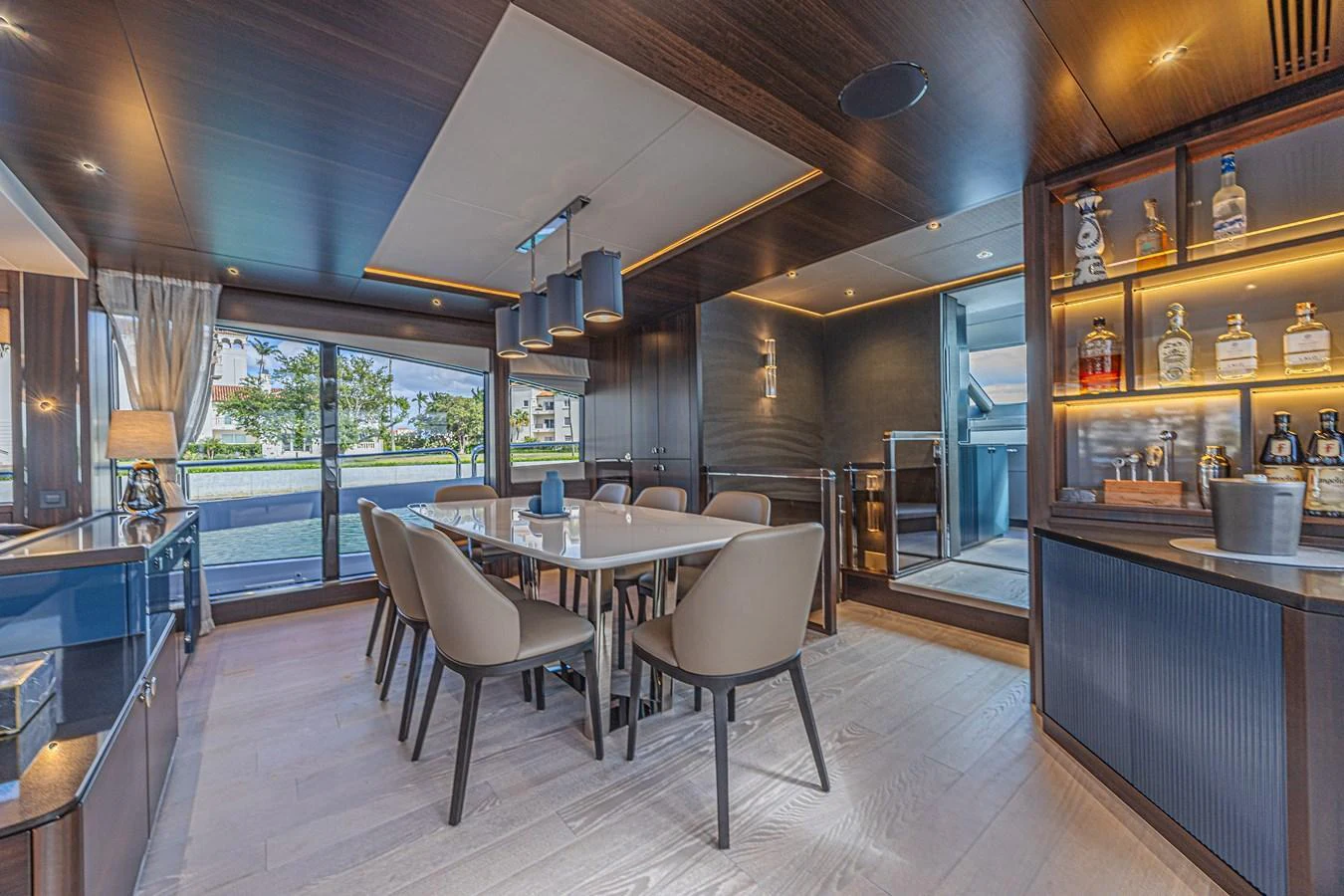 The yacht's dining area features a modern table surrounded by elegant chairs, with a view of the outside through large windows. aboard HIDEOUT Yacht for Sale
