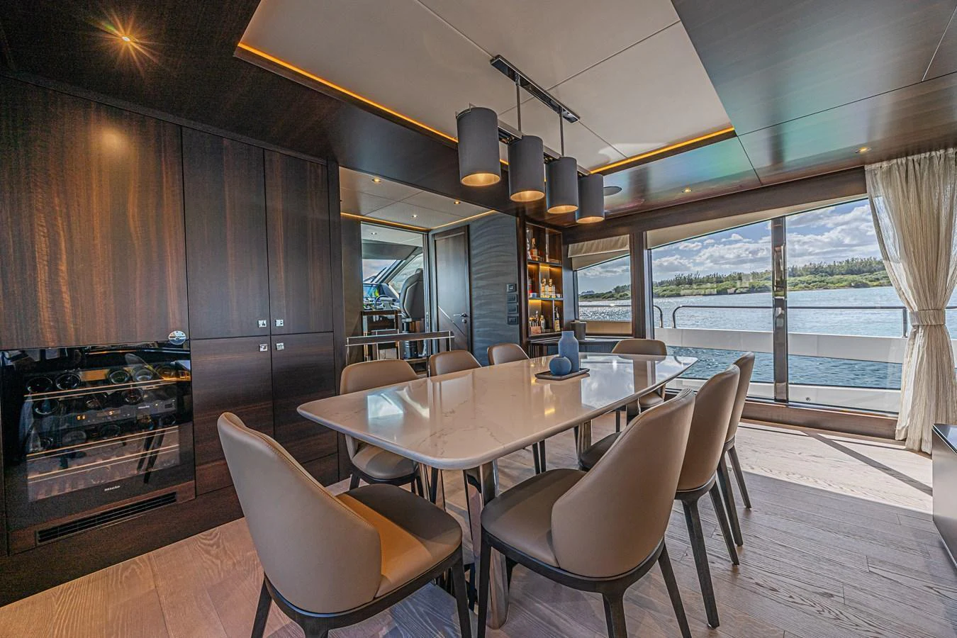 The yacht's dining area features a sleek, modern design with a large table and comfortable seating, complemented by panoramic windows offering stunning water views. aboard HIDEOUT Yacht for Sale