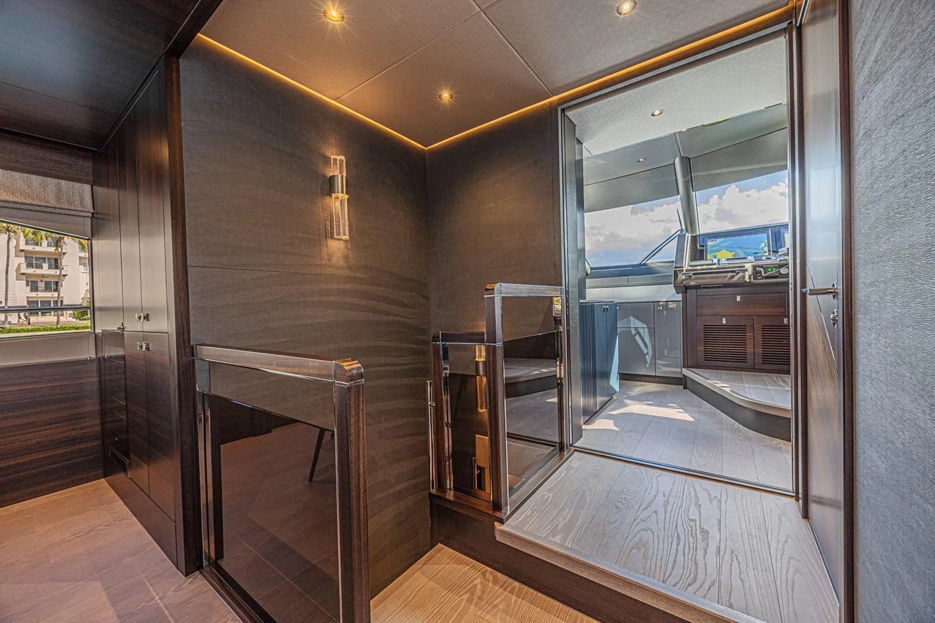 The image showcases a modern interior space with sleek, dark wood finishes and a view into the helm area. aboard HIDEOUT Yacht for Sale