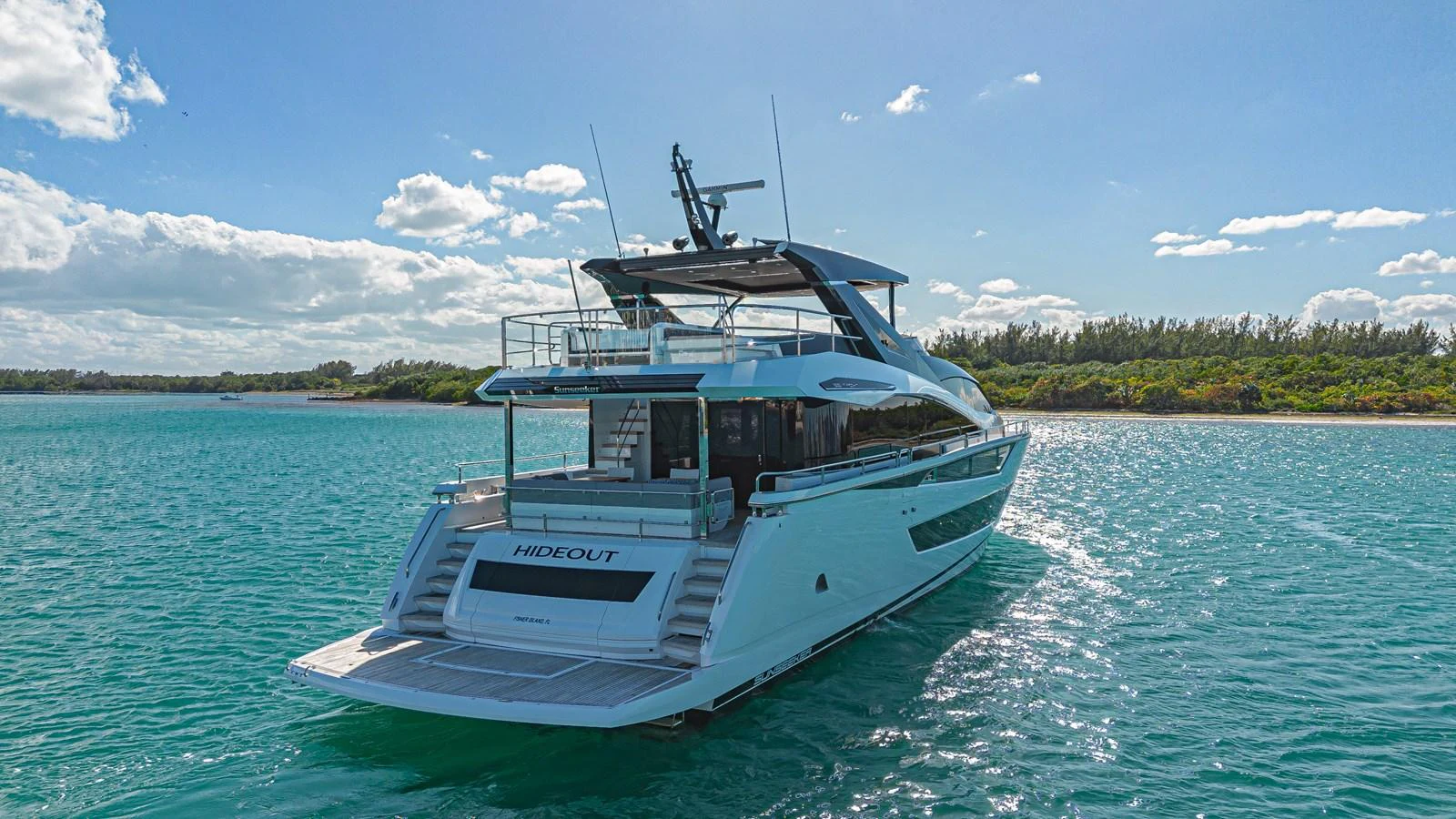 A sleek and modern yacht glides gracefully on serene turquoise waters under a clear sky. aboard HIDEOUT Yacht for Sale
