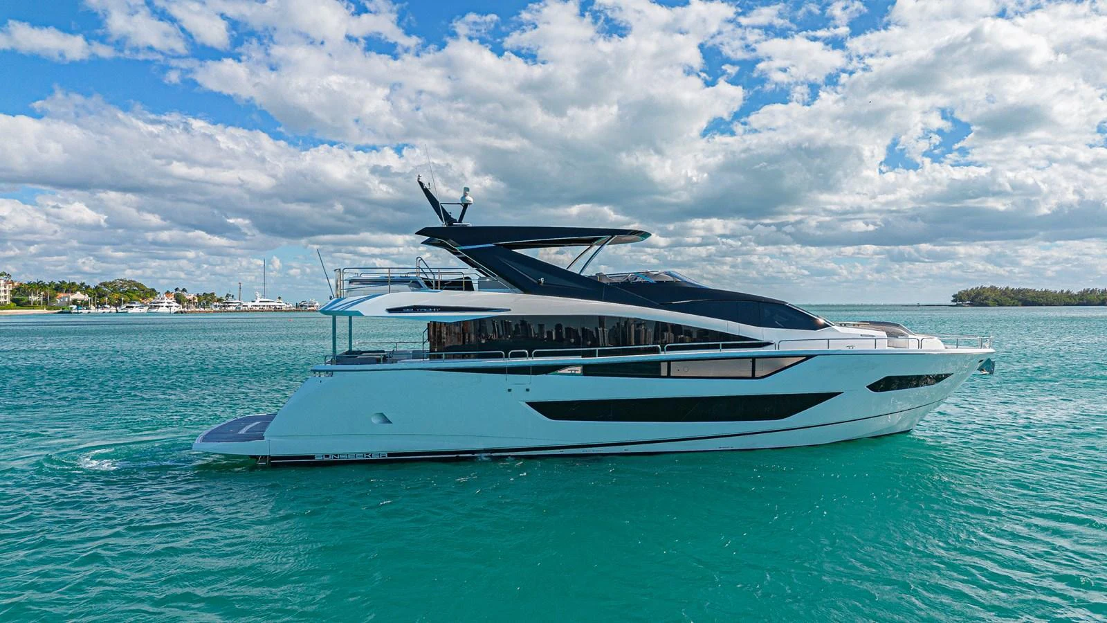 A sleek and modern yacht glides gracefully on turquoise waters under a partly cloudy sky. aboard HIDEOUT Yacht for Sale