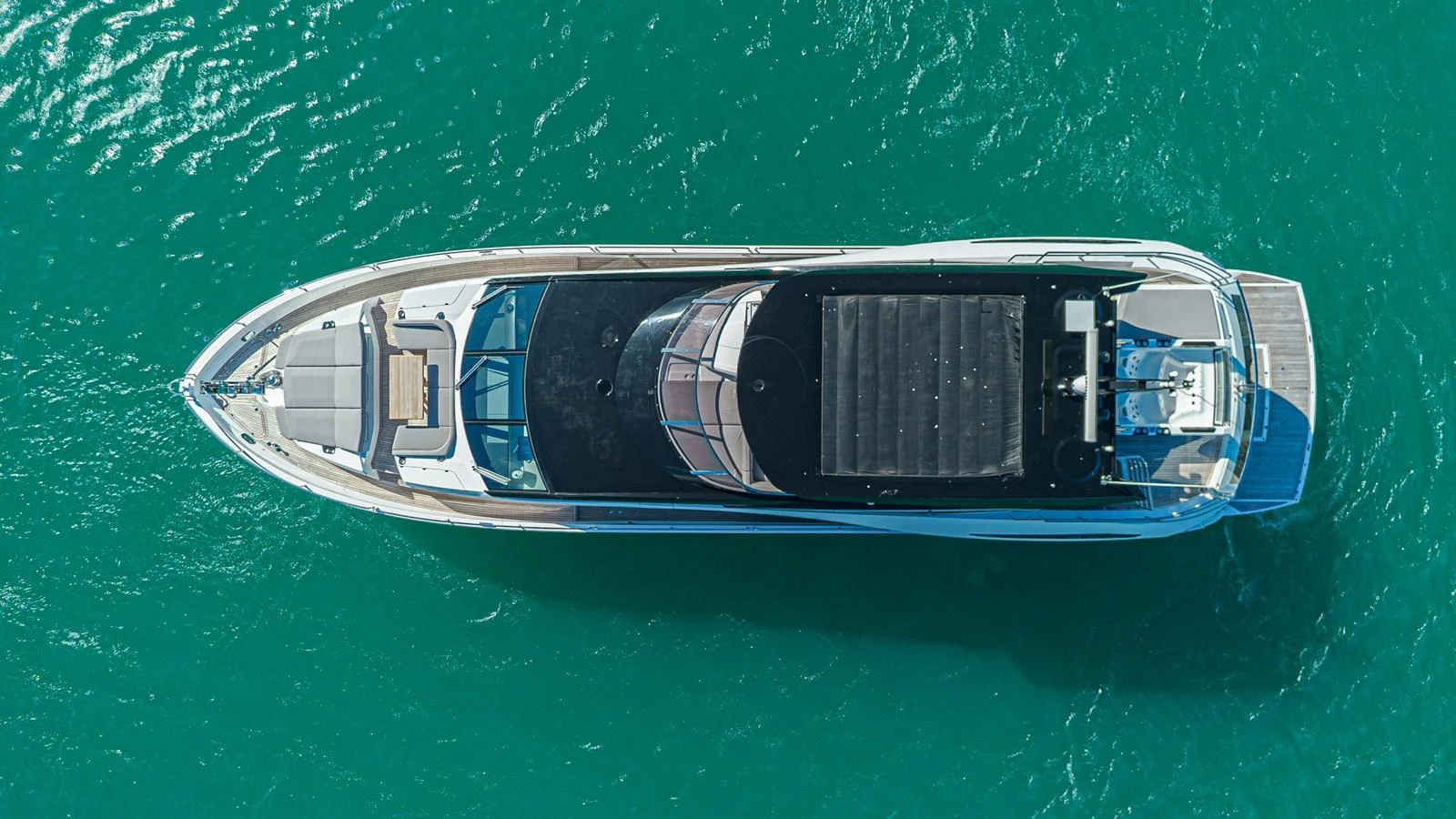 A sleek yacht cruising on clear turquoise waters, viewed from above. aboard HIDEOUT Yacht for Sale