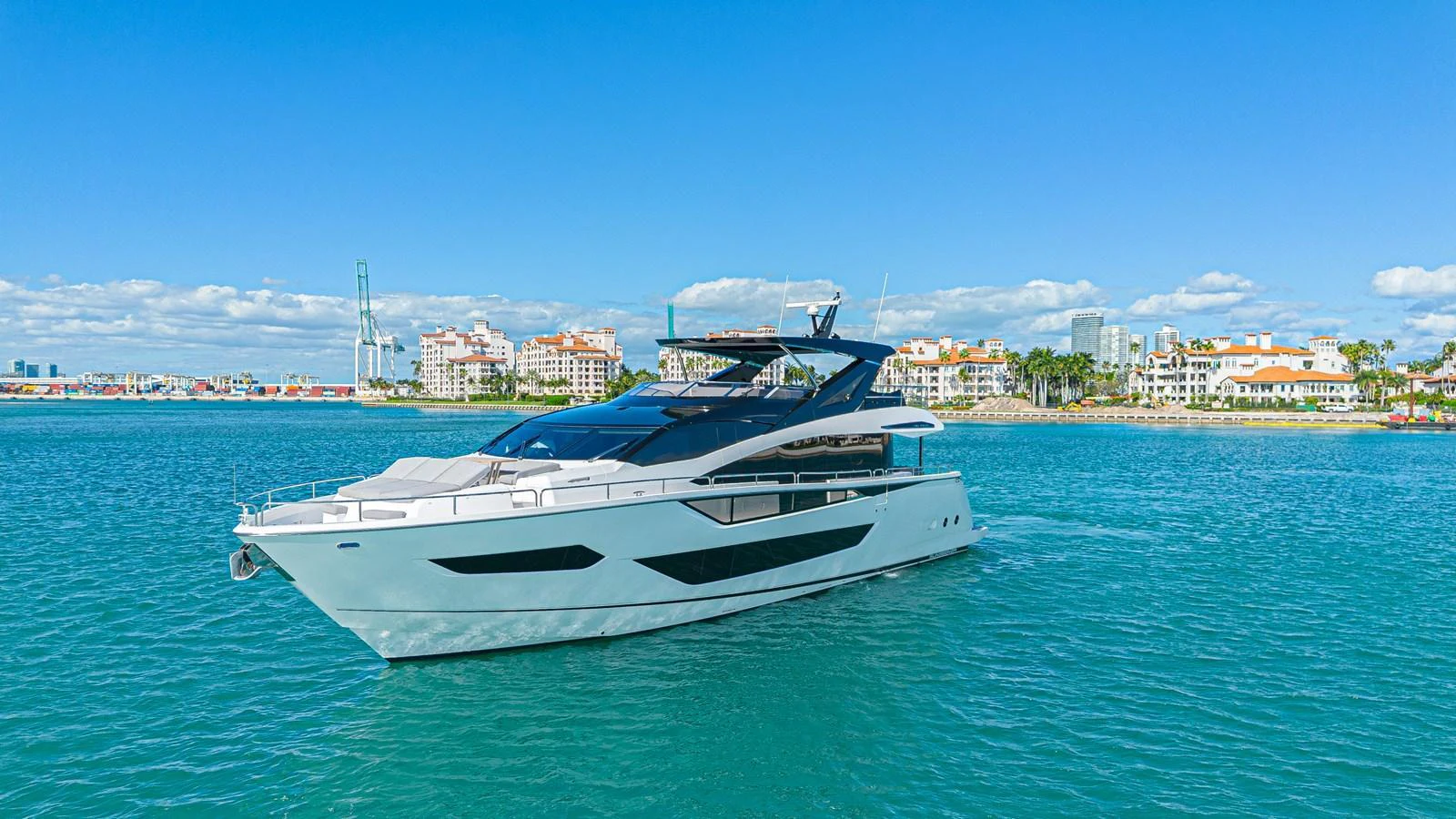 A sleek and modern yacht cruising on clear blue waters with a scenic coastal backdrop. aboard HIDEOUT Yacht for Sale