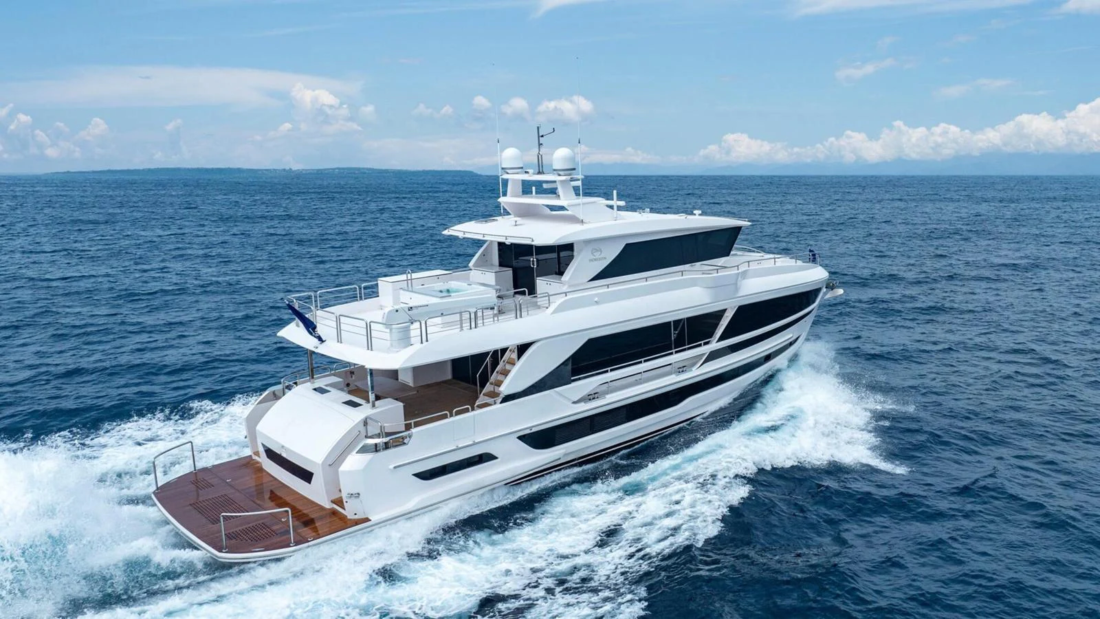 A sleek and modern yacht cruising through the open sea under a clear blue sky. aboard HAPPY HEART Yacht for Sale