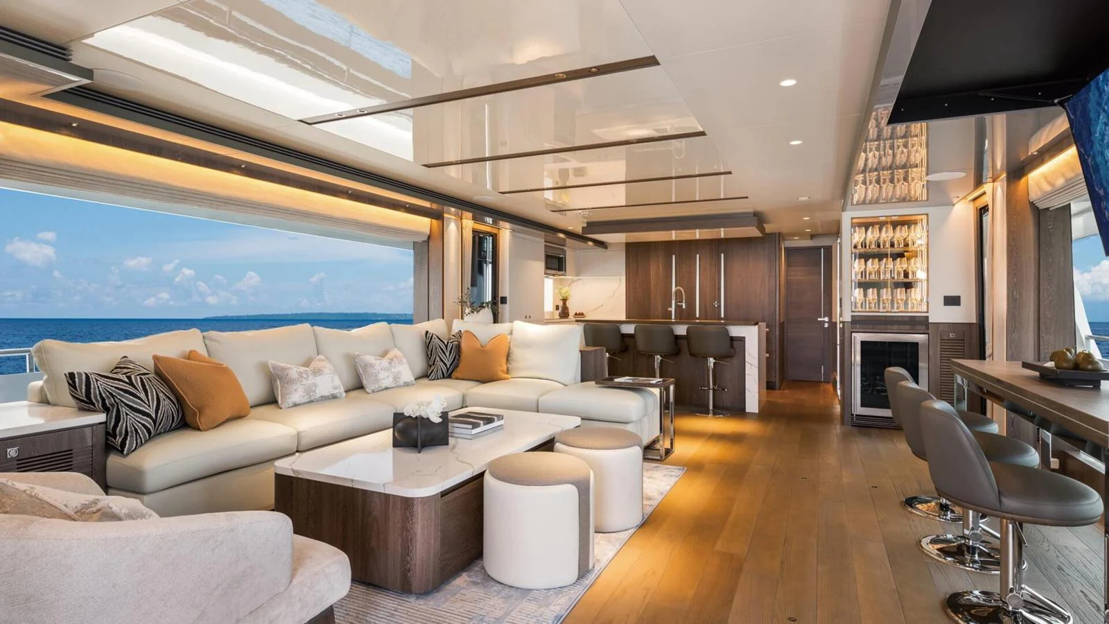 The spacious salon features elegant seating, a modern kitchen, and expansive windows with ocean views. aboard HAPPY HEART Yacht for Sale