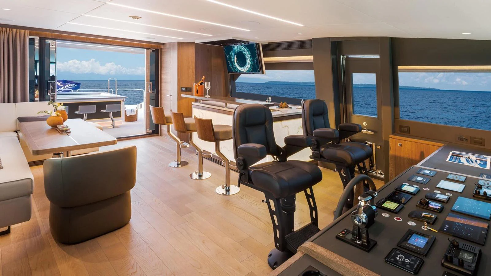 The helm area features modern controls, comfortable seating, and a view of the open sea. aboard HAPPY HEART Yacht for Sale