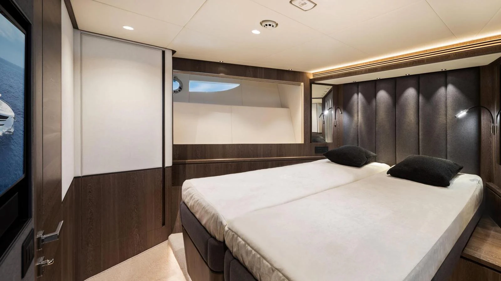 The stateroom features a luxurious double bed with modern lighting and elegant wood paneling. aboard HAPPY HEART Yacht for Sale