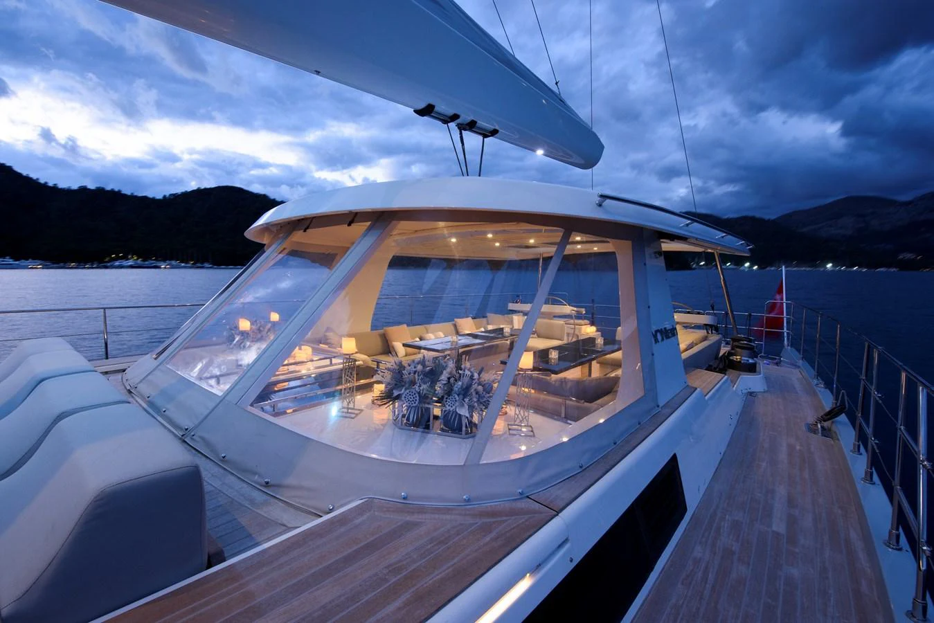 The yacht's sleek exterior features expansive windows offering a glimpse into the luxurious interior, set against a serene twilight backdrop. aboard MISHI Yacht for Sale