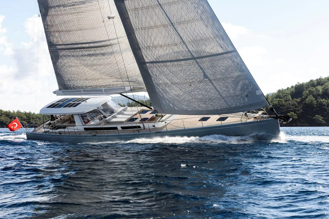 A sleek sailing yacht glides gracefully through the water, showcasing its impressive sails and modern design. aboard MISHI Yacht for Sale