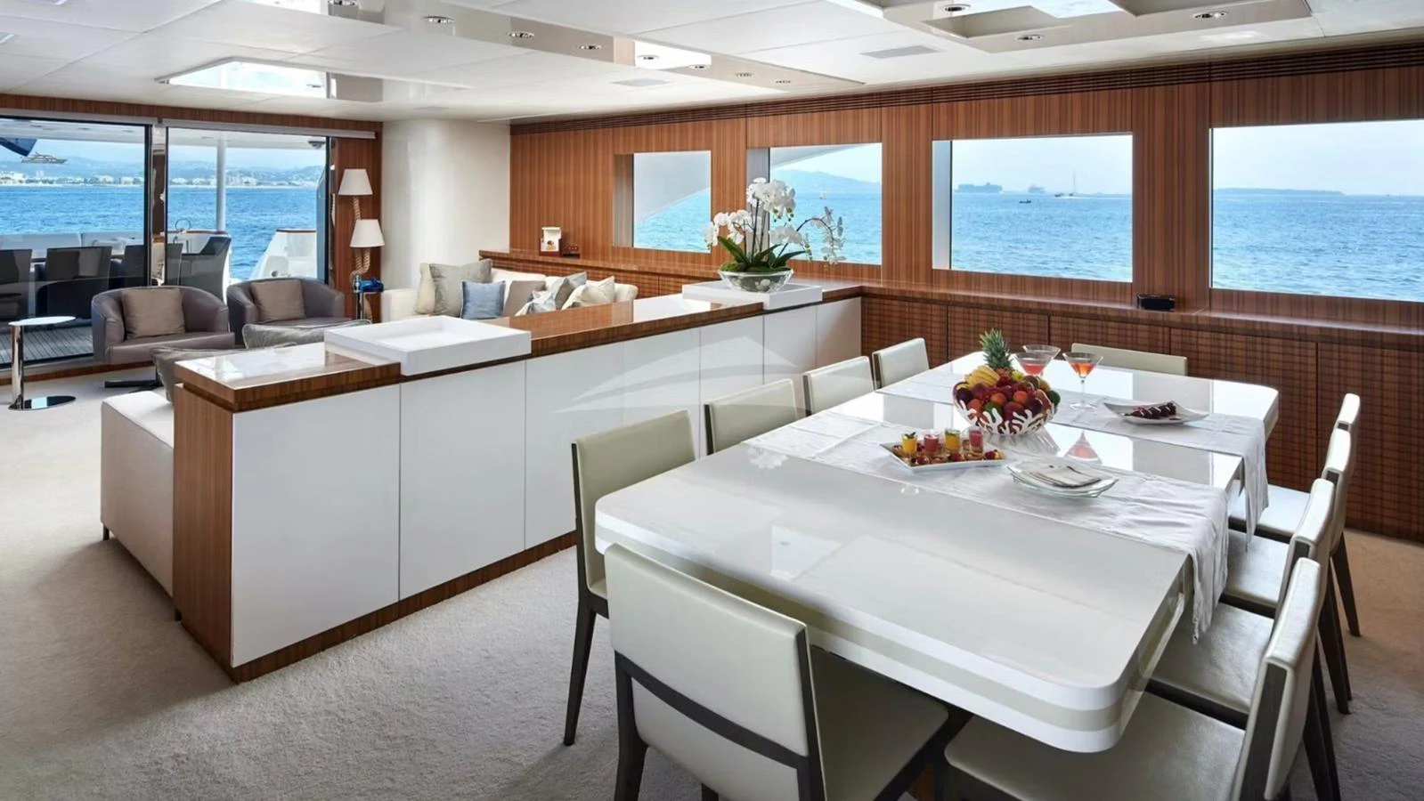 The yacht's dining area features a modern table set against large windows with a stunning sea view. aboard SEA SHELL Yacht for Sale