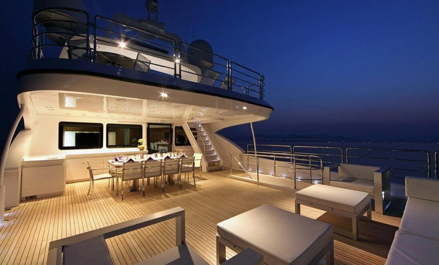 The aft deck of the yacht offers an elegant dining area and comfortable seating under the evening sky. aboard SEA SHELL Yacht for Sale