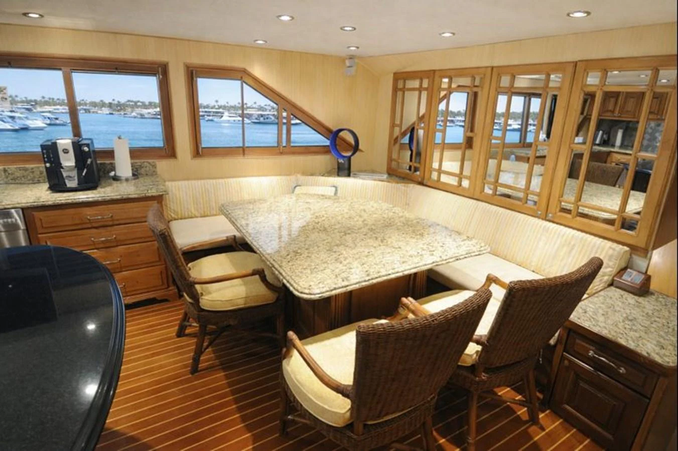 The yacht's dining area features a spacious table with comfortable wicker chairs and panoramic windows offering stunning views. aboard BURNING DAYLIGHT Yacht for Sale