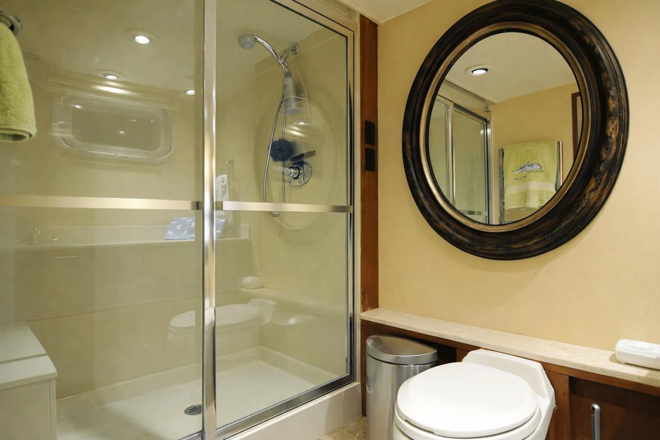 A well-appointed yacht bathroom featuring a glass-enclosed shower and a round mirror above the sink. aboard BURNING DAYLIGHT Yacht for Sale