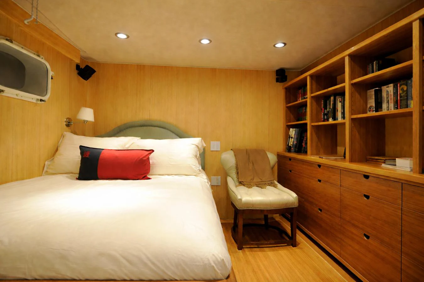 The cozy stateroom features a comfortable bed, built-in bookshelves, and warm lighting. aboard BURNING DAYLIGHT Yacht for Sale