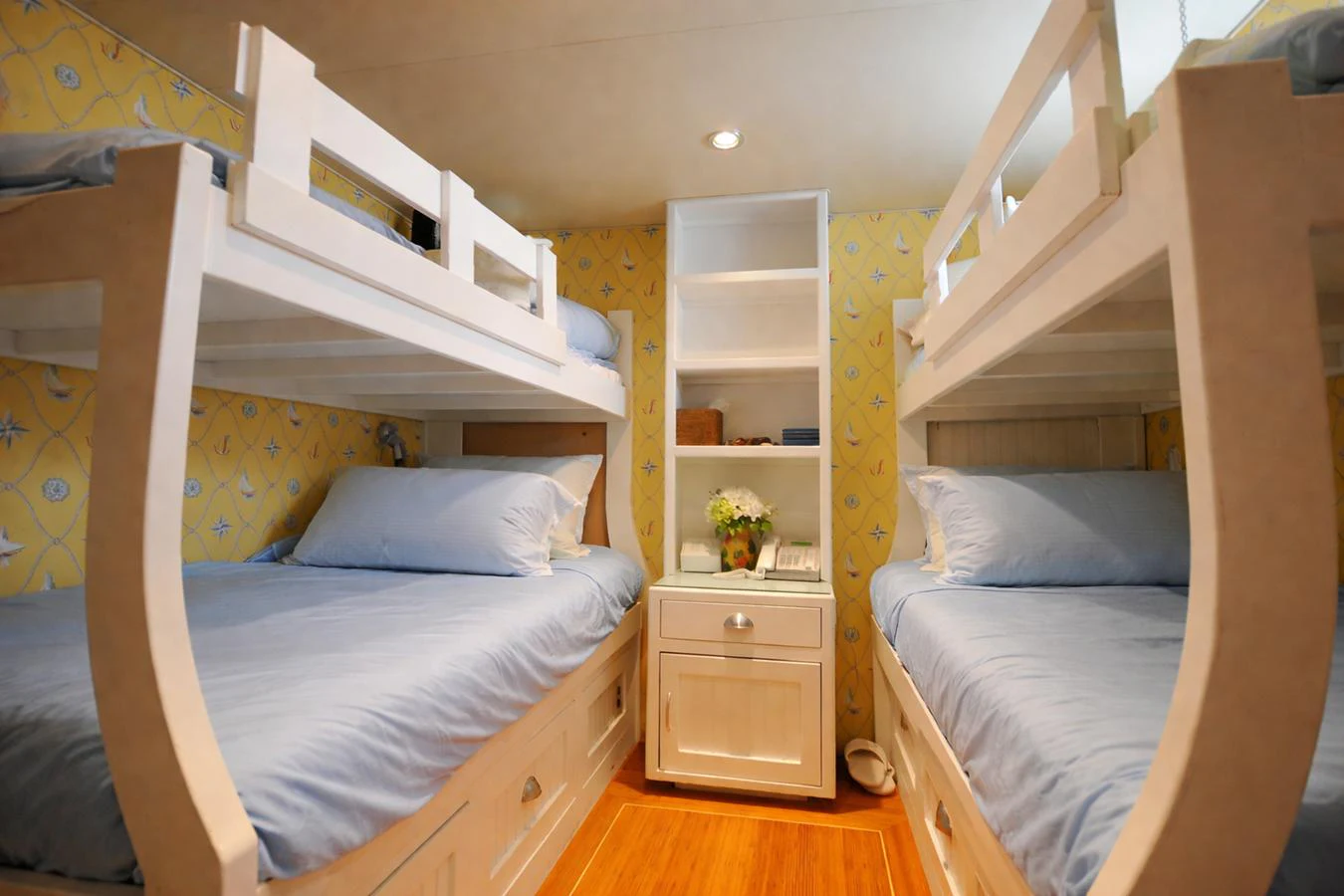 The cozy bunk room features two sets of bunk beds with soft blue bedding and a central nightstand. aboard BURNING DAYLIGHT Yacht for Sale