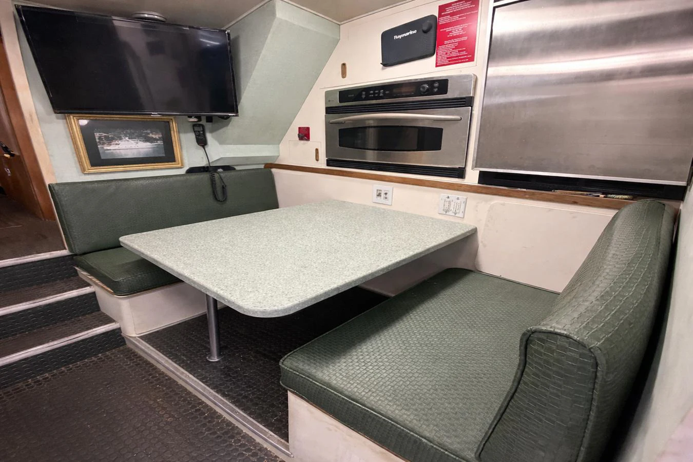 The yacht's galley features a cozy dining nook with a table and built-in seating, complemented by modern appliances. aboard BURNING DAYLIGHT Yacht for Sale