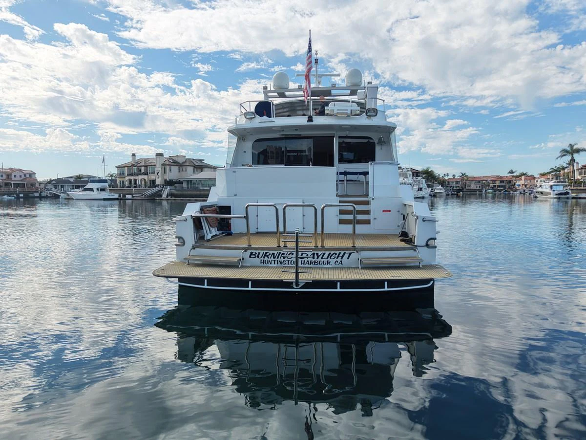 The yacht is docked in a serene marina, showcasing its spacious aft deck and inviting ambiance. aboard BURNING DAYLIGHT Yacht for Sale