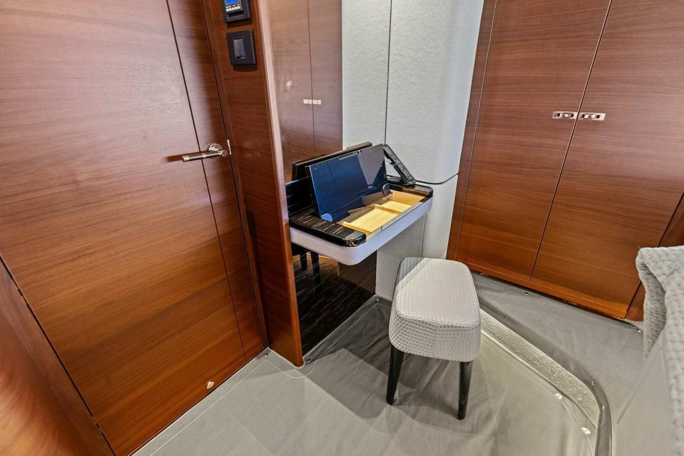 A cozy interior space featuring a small desk area with a laptop and a stool. aboard 3BBOYS Yacht for Sale