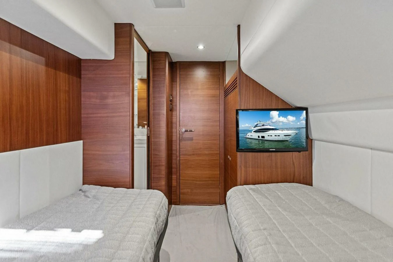 The guest cabin features twin beds, wood paneling, and a mounted TV. aboard 3BBOYS Yacht for Sale