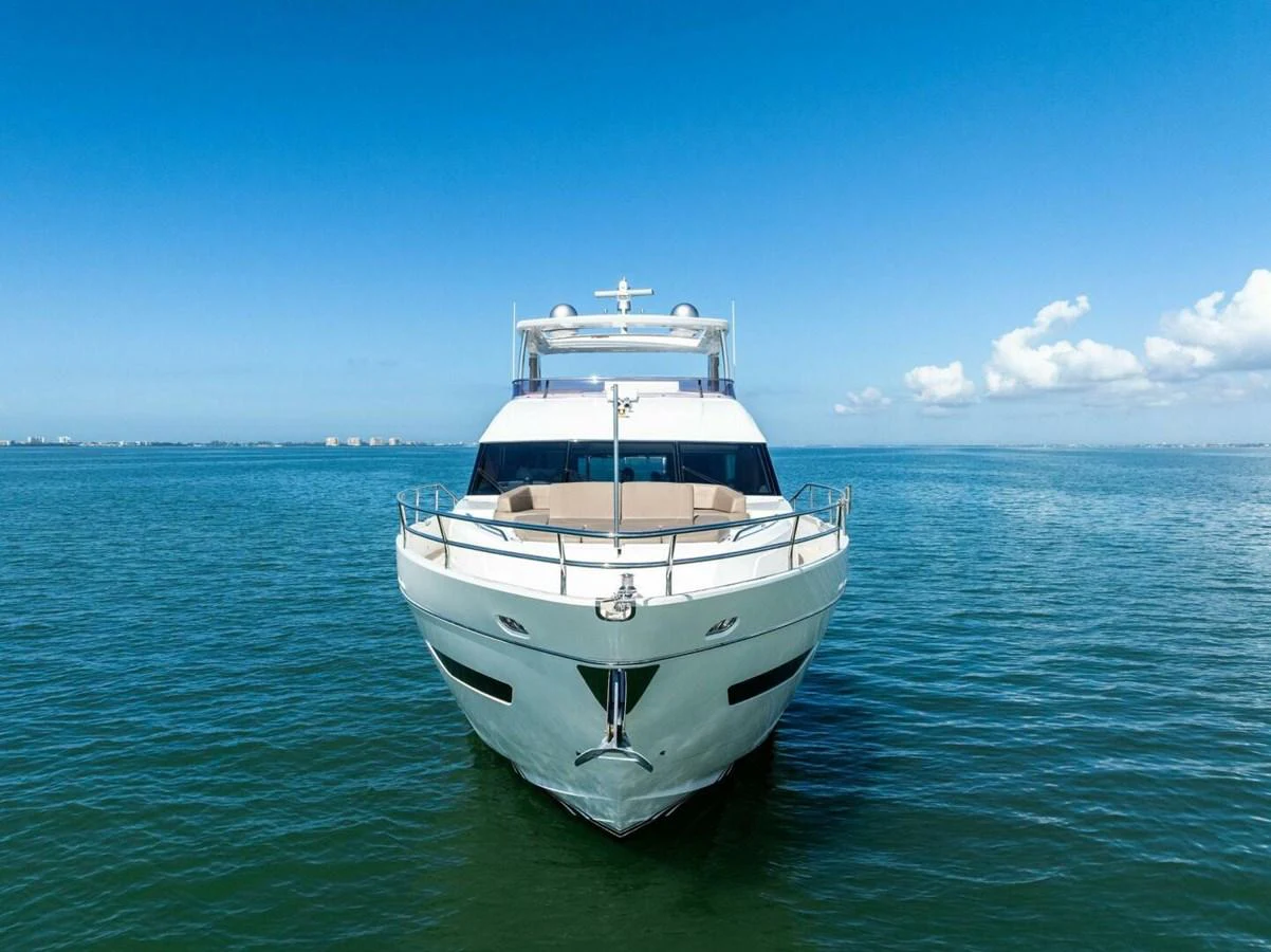 A sleek yacht is seen head-on, cruising on calm blue waters under a clear sky. aboard 3BBOYS Yacht for Sale