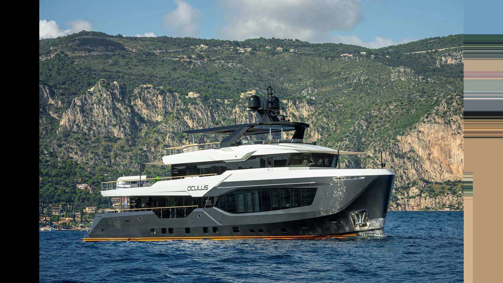 A luxurious yacht cruises along a scenic coastline with rugged hills in the background. aboard NUMARINE 37XP-21 Yacht for Sale