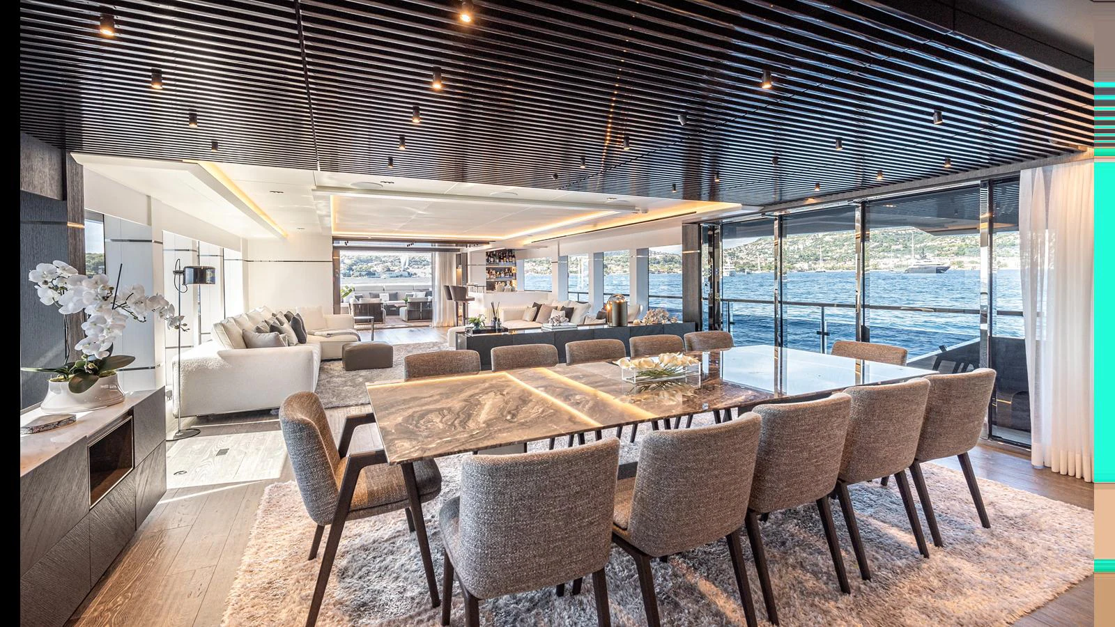 The yacht's dining area features a large table with plush seating and expansive windows offering stunning water views. aboard NUMARINE 37XP-21 Yacht for Sale