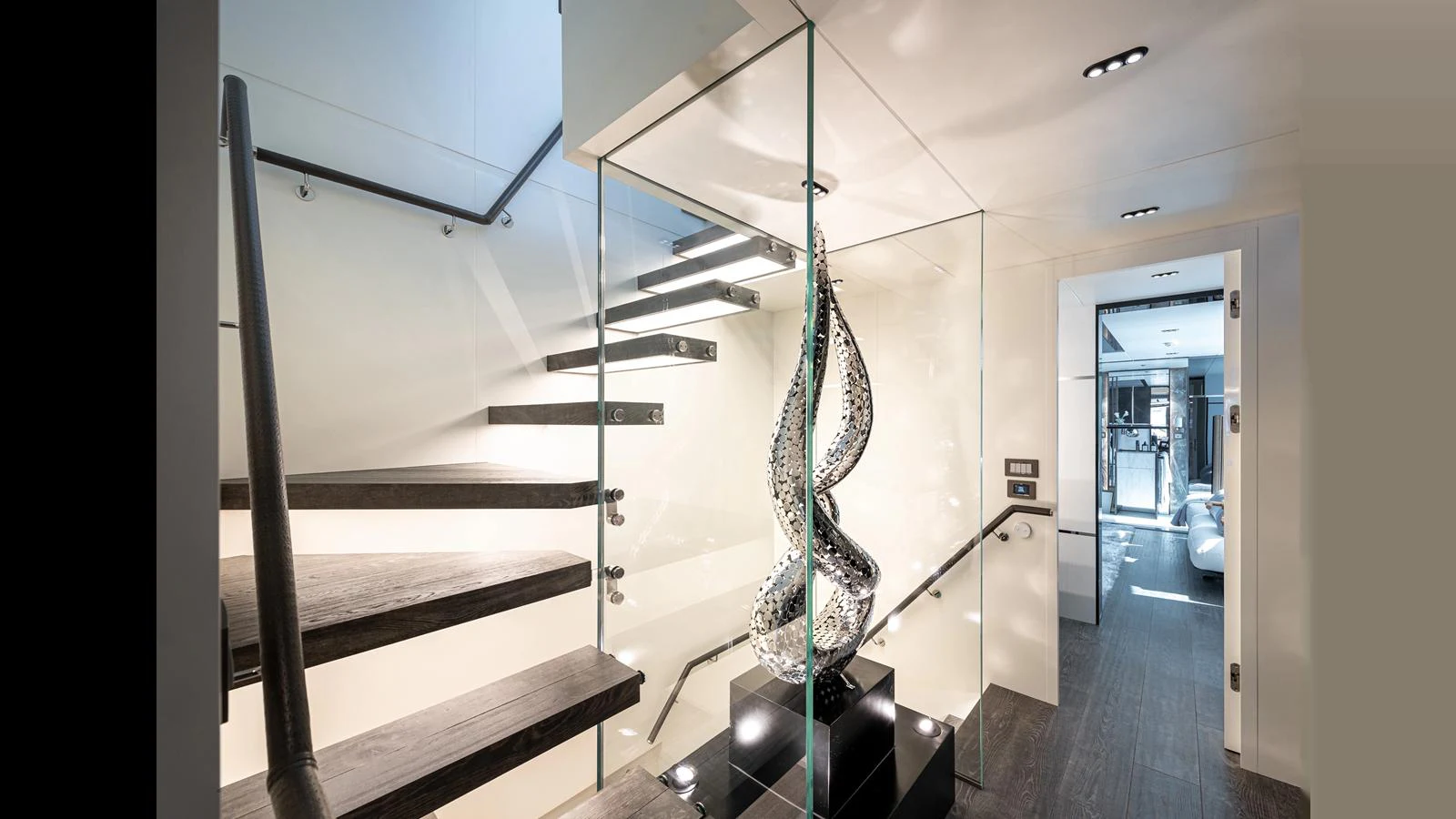 A modern yacht interior featuring a sleek staircase with glass railings and a contemporary sculpture. aboard NUMARINE 37XP-21 Yacht for Sale