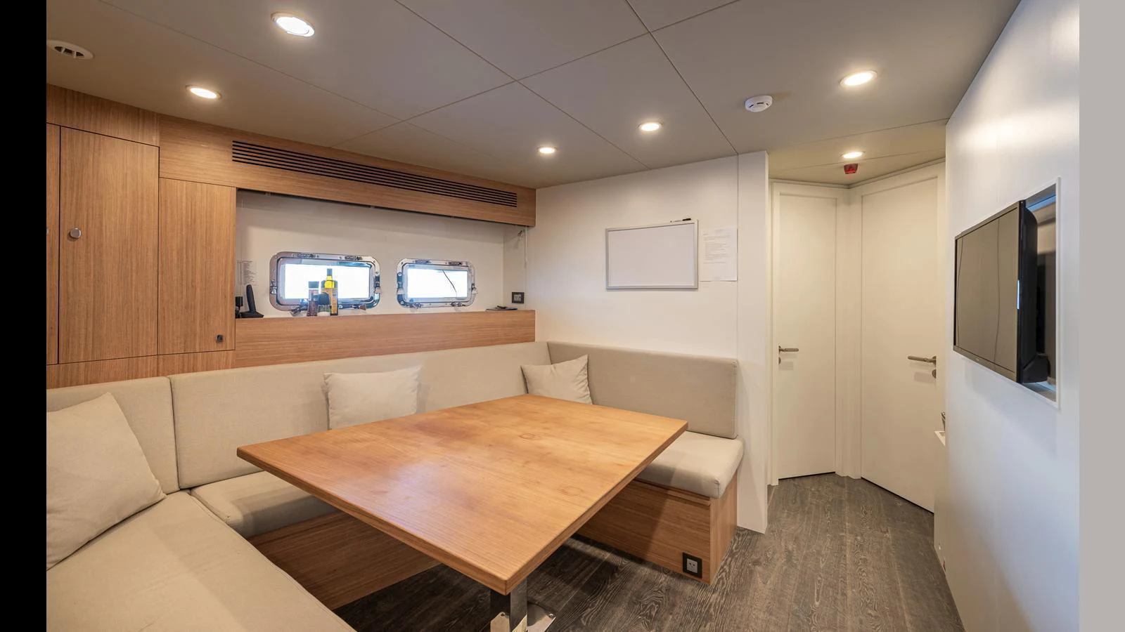 The yacht's dining area features a cozy seating arrangement with a wooden table and modern decor. aboard NUMARINE 37XP-21 Yacht for Sale