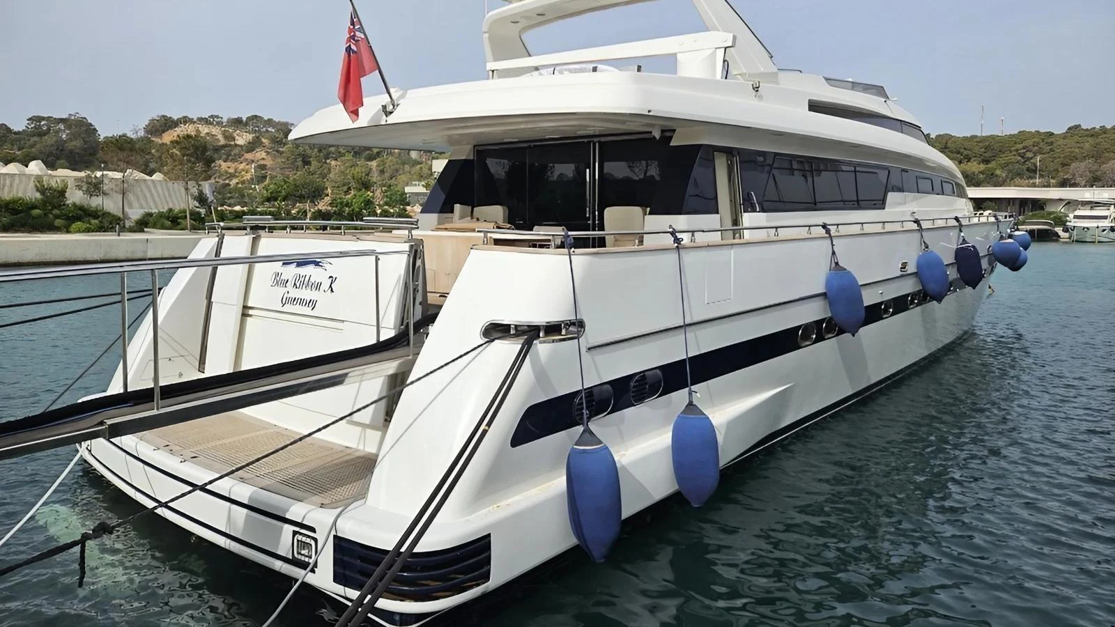 A sleek and modern yacht is docked, showcasing its elegant aft deck and clean lines. aboard BLUE RIBBON Yacht for Sale
