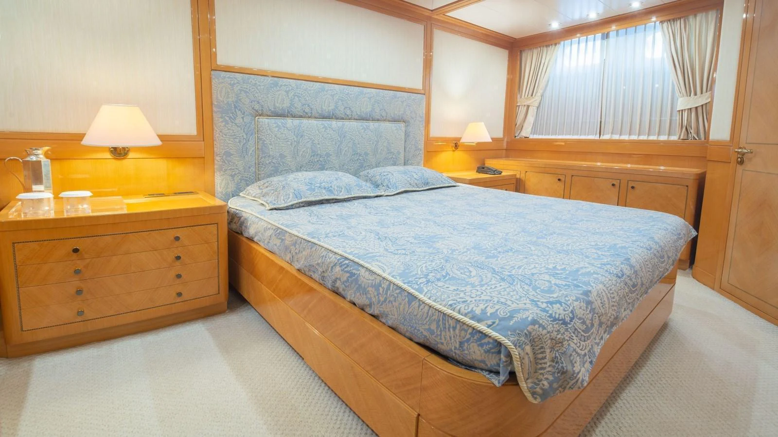 The master stateroom features a luxurious bed with elegant bedding and warm wood finishes. aboard BLUE RIBBON Yacht for Sale