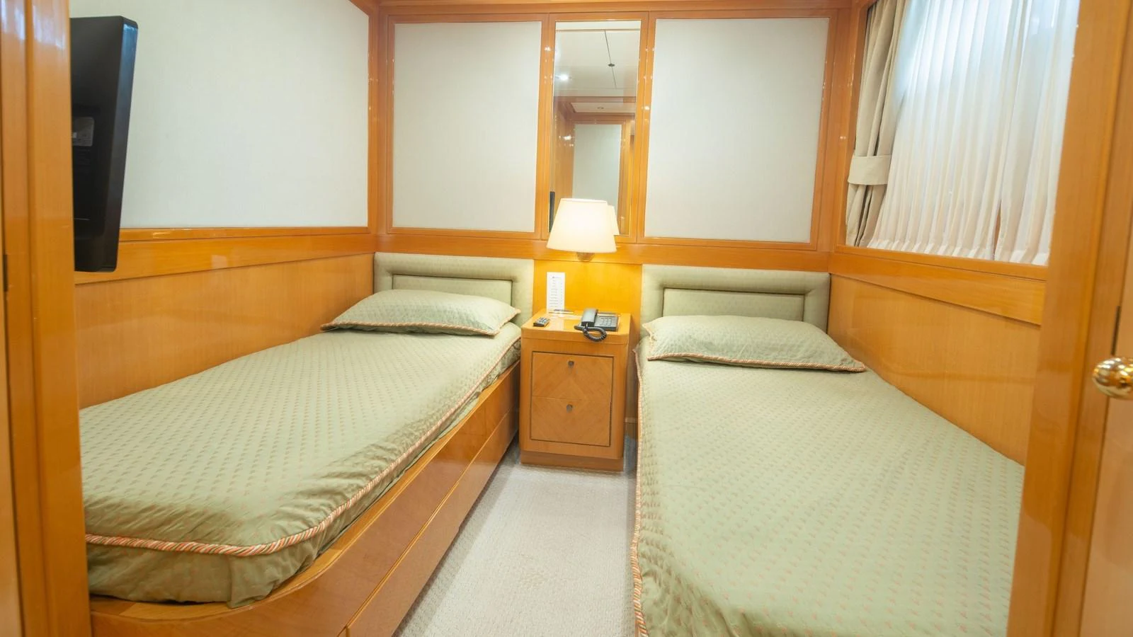 The twin stateroom features two single beds with a warm wood finish and soft lighting. aboard BLUE RIBBON Yacht for Sale