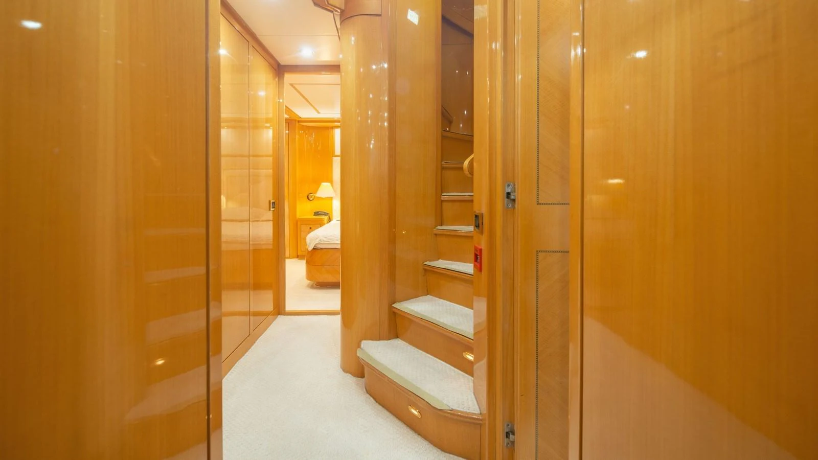 The image showcases a luxurious hallway with wooden paneling and a staircase leading to the upper deck. aboard BLUE RIBBON Yacht for Sale