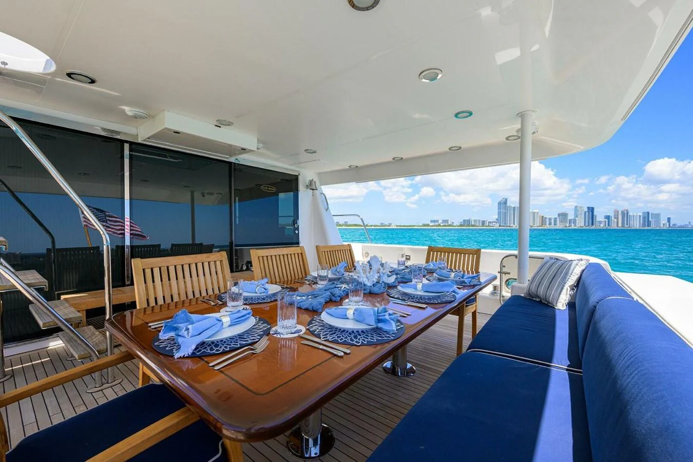 a table with blue cloths on it and chairs on a deck with a body of water in aboard JULE Yacht for Sale